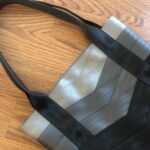 seat belt tote in shades of grey laying on floor